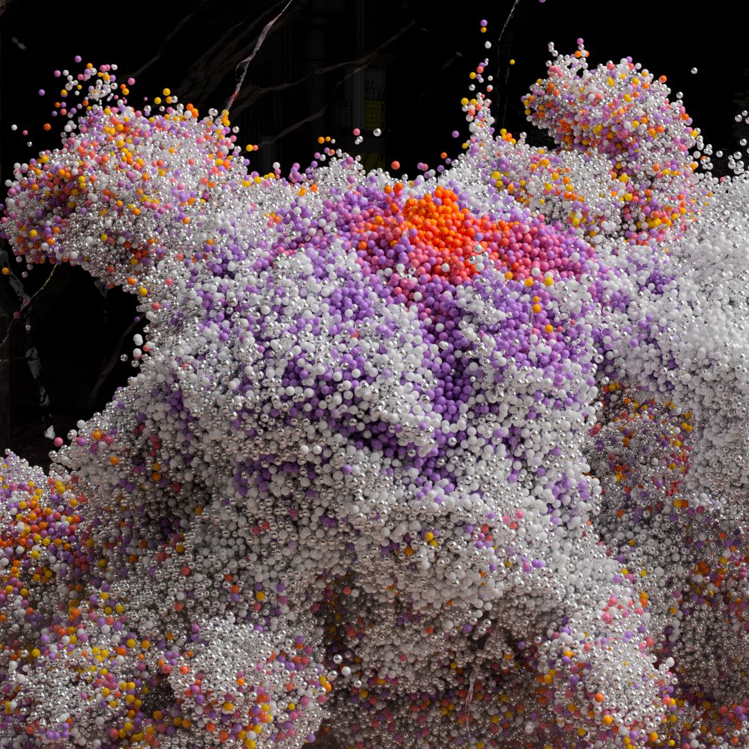 Close-up of a billowing mass of tiny silver, white, lilac and orange beads, with a bright orange patch at its centre.