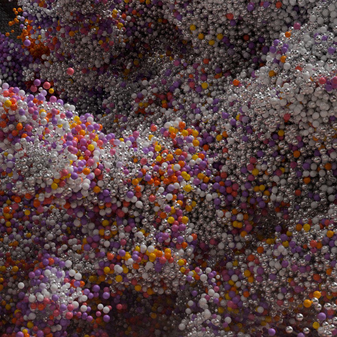 Close-up of rolling waves of thousands of small metallic, purple, orange and yellow beads.